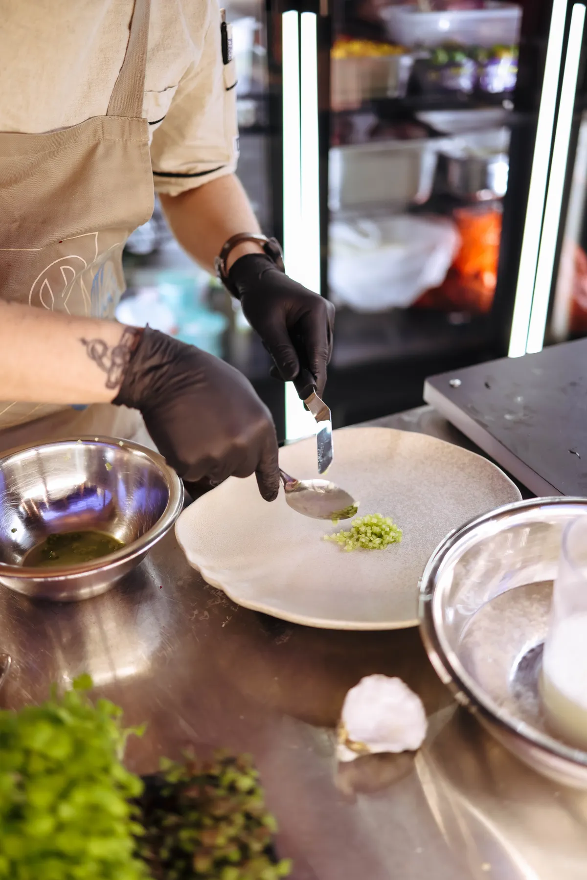 A chef uses two spoons to finish a small green garnish on a plate.